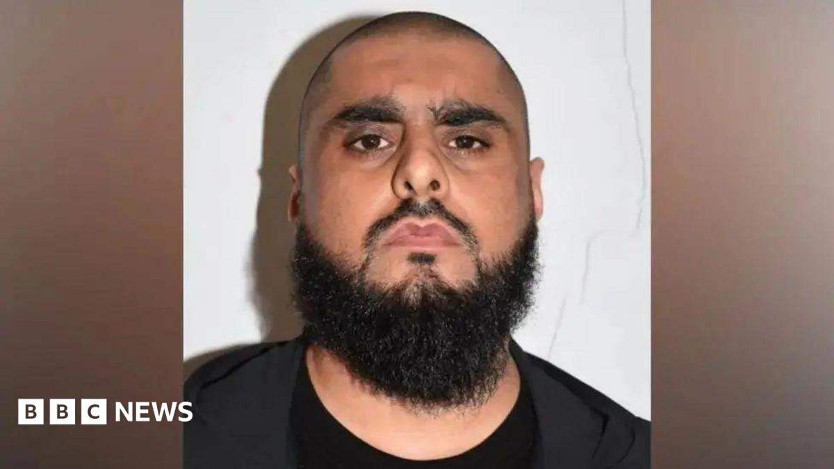 Man with shaven hair and dark beard in black clothing