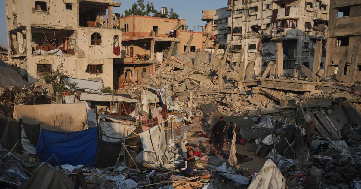 Palestinians salvage their belongings from the rubble of a building and tents destroyed in an Israeli airstrike in Gaza