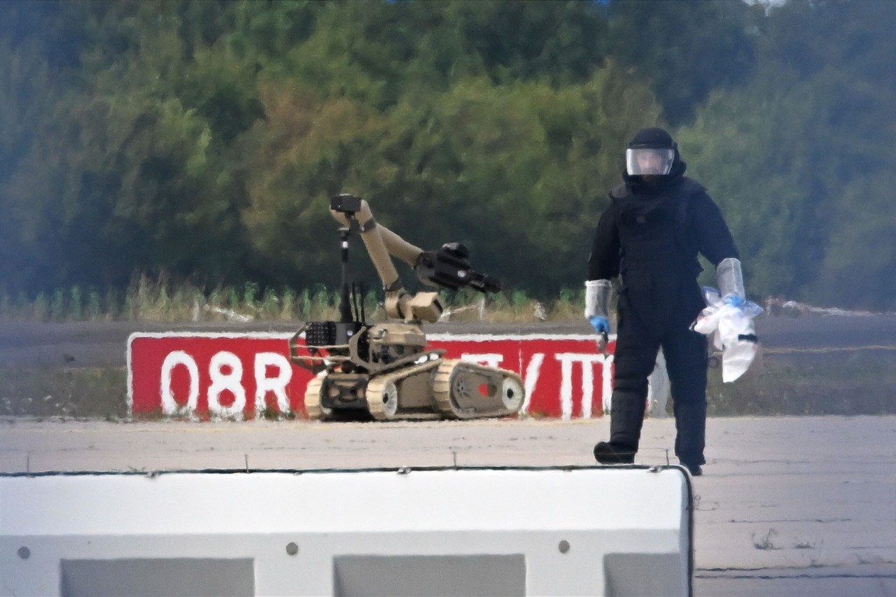 A forensic technician works alongside a bomb-disposal robot near a Ukrainian aircraft at Leipzig/Halle Airport, where a