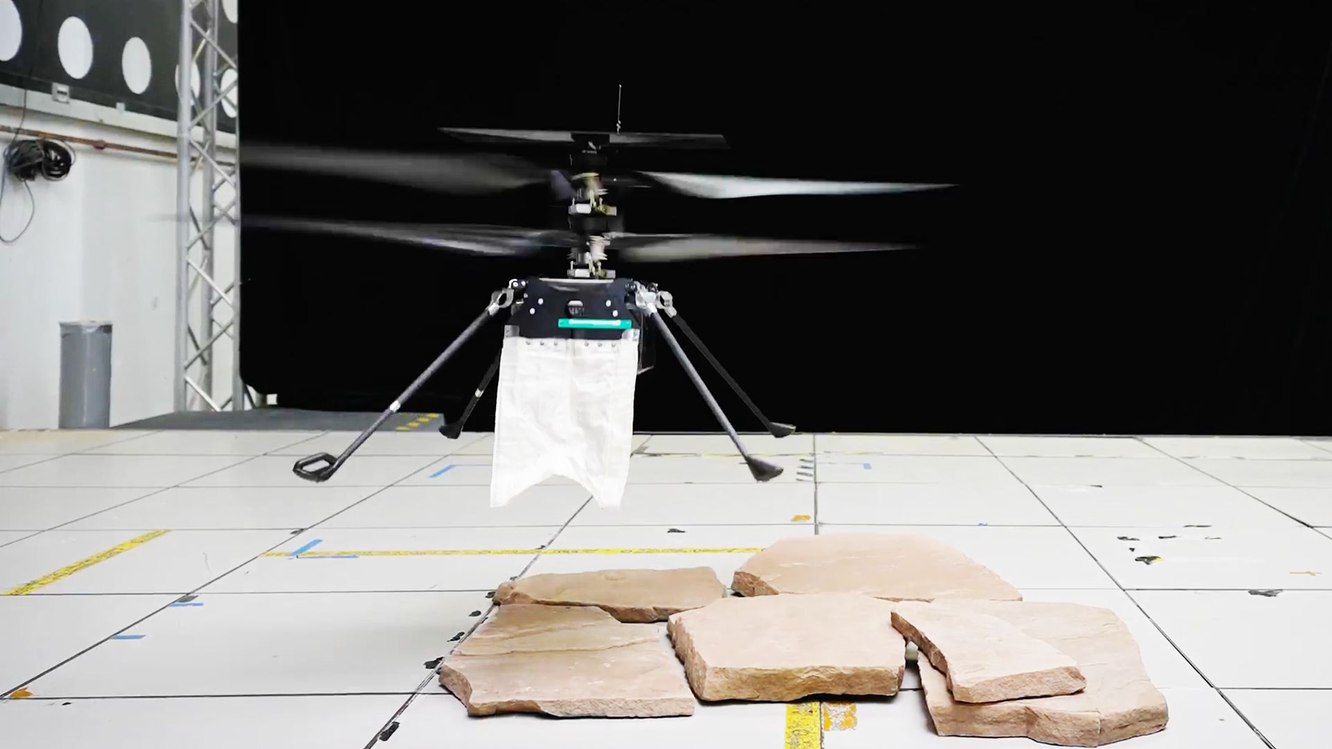 A tiny helicopter drone has a small white cape